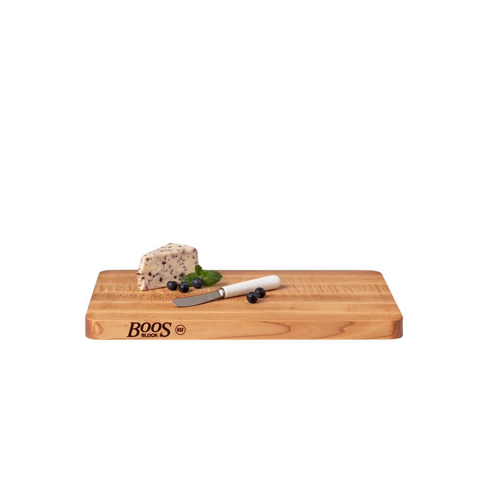 Wooden cutting board with a block of cheese, knife, and berries 