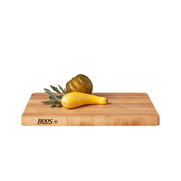 A wooden cutting board by Boos Block with a two different squashes and sage 
