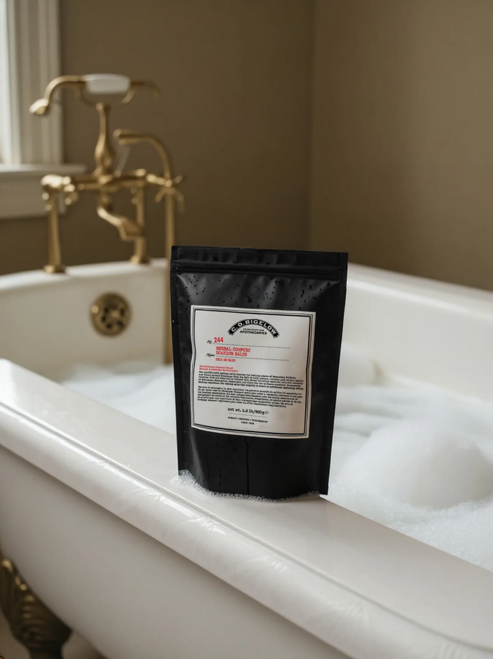 C O Bigelow bag of Herbal Soaking Salts on a white bathtub filled with bubbles