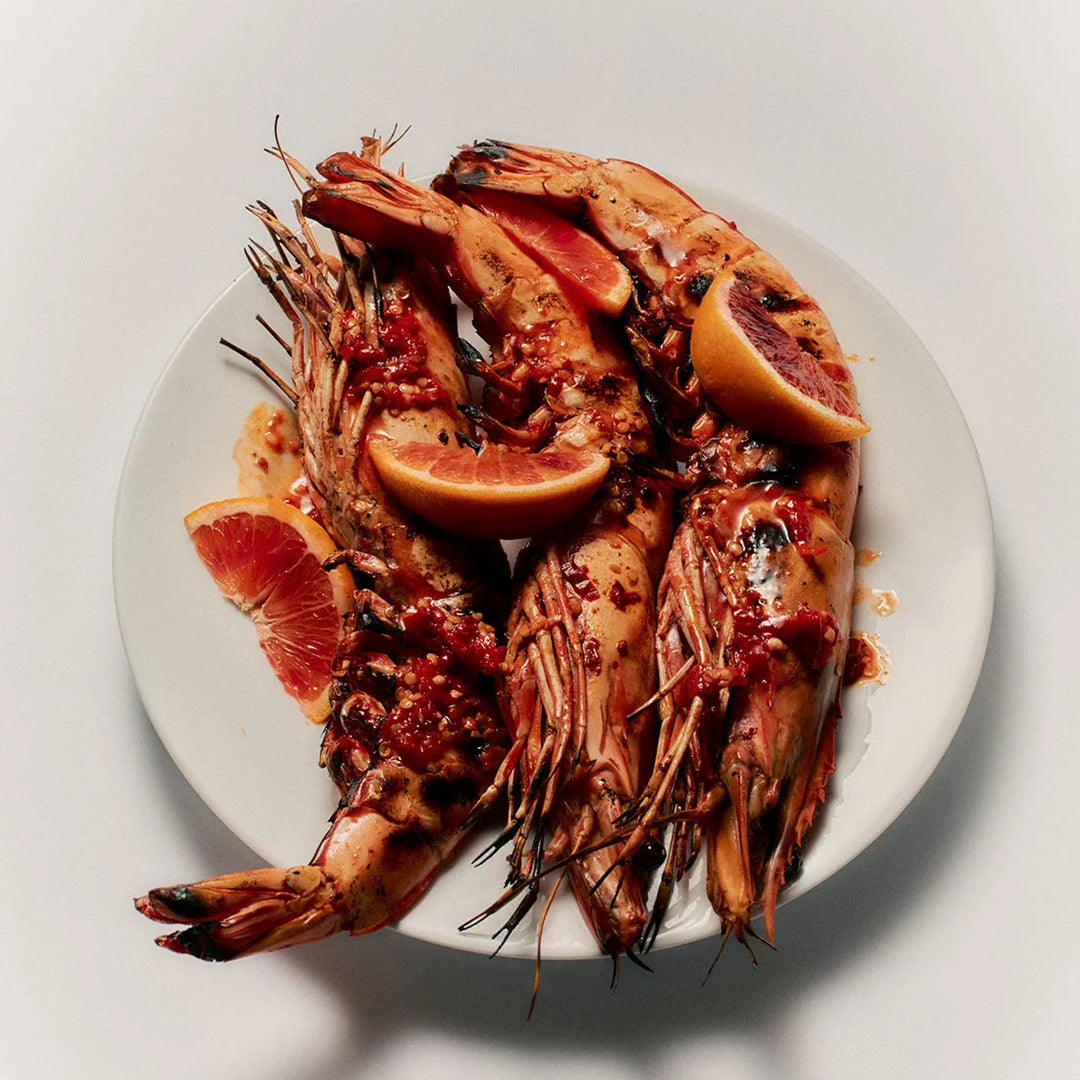 Plated seafood dish with prawns and grapefruit on a white background