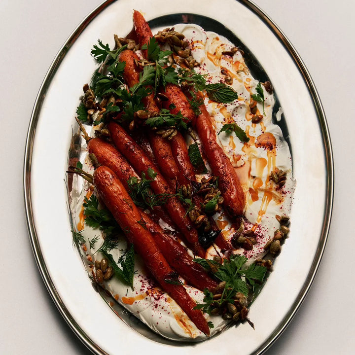 Plated dish of roasted carrots with herbs and a sauce 