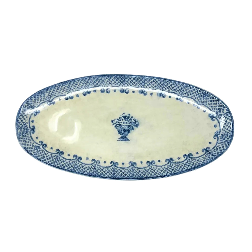 An oval ceramic serving platter with a blue and white glaze, featuring a central floral motif and a patterned border.