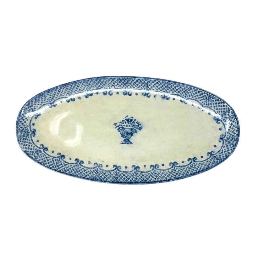 An oval ceramic serving platter with a blue and white glaze, featuring a central floral motif and a patterned border.