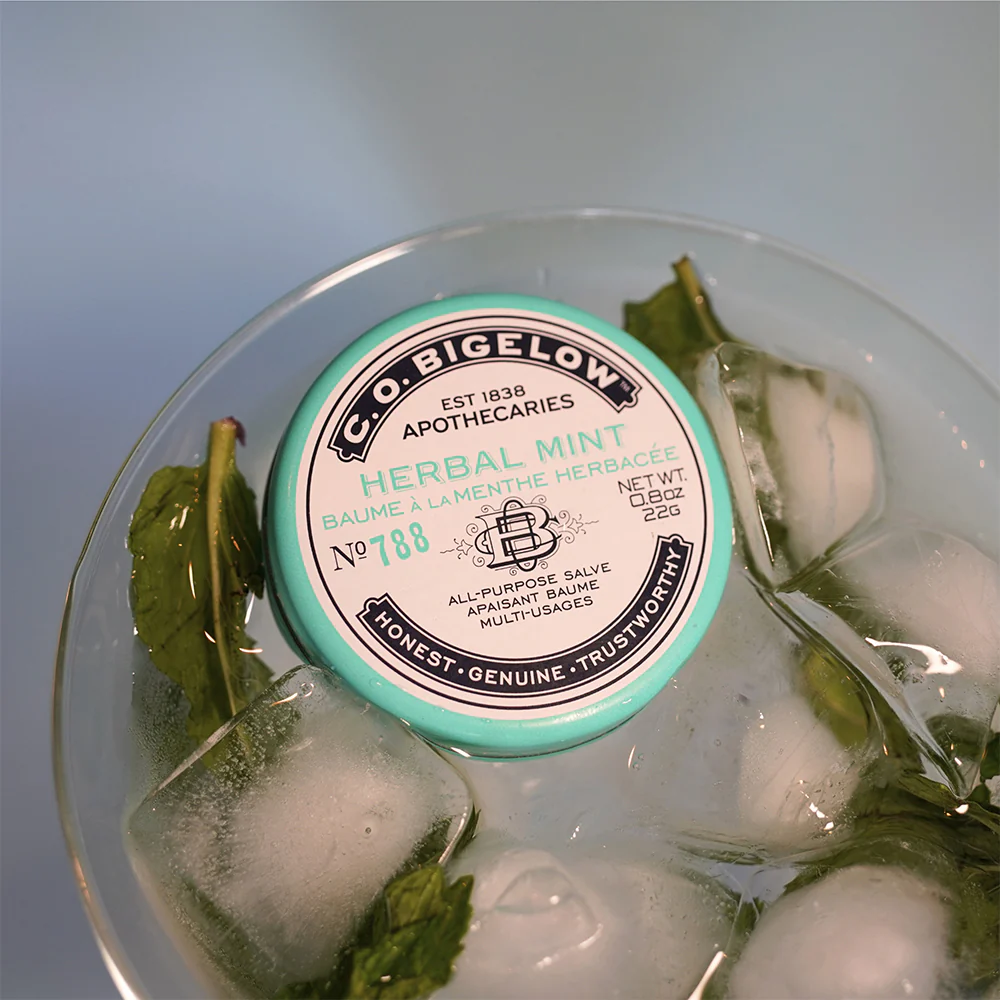 C.O. Bigelow Herbal Mint balm in a glass bowl with ice and mint leaves
