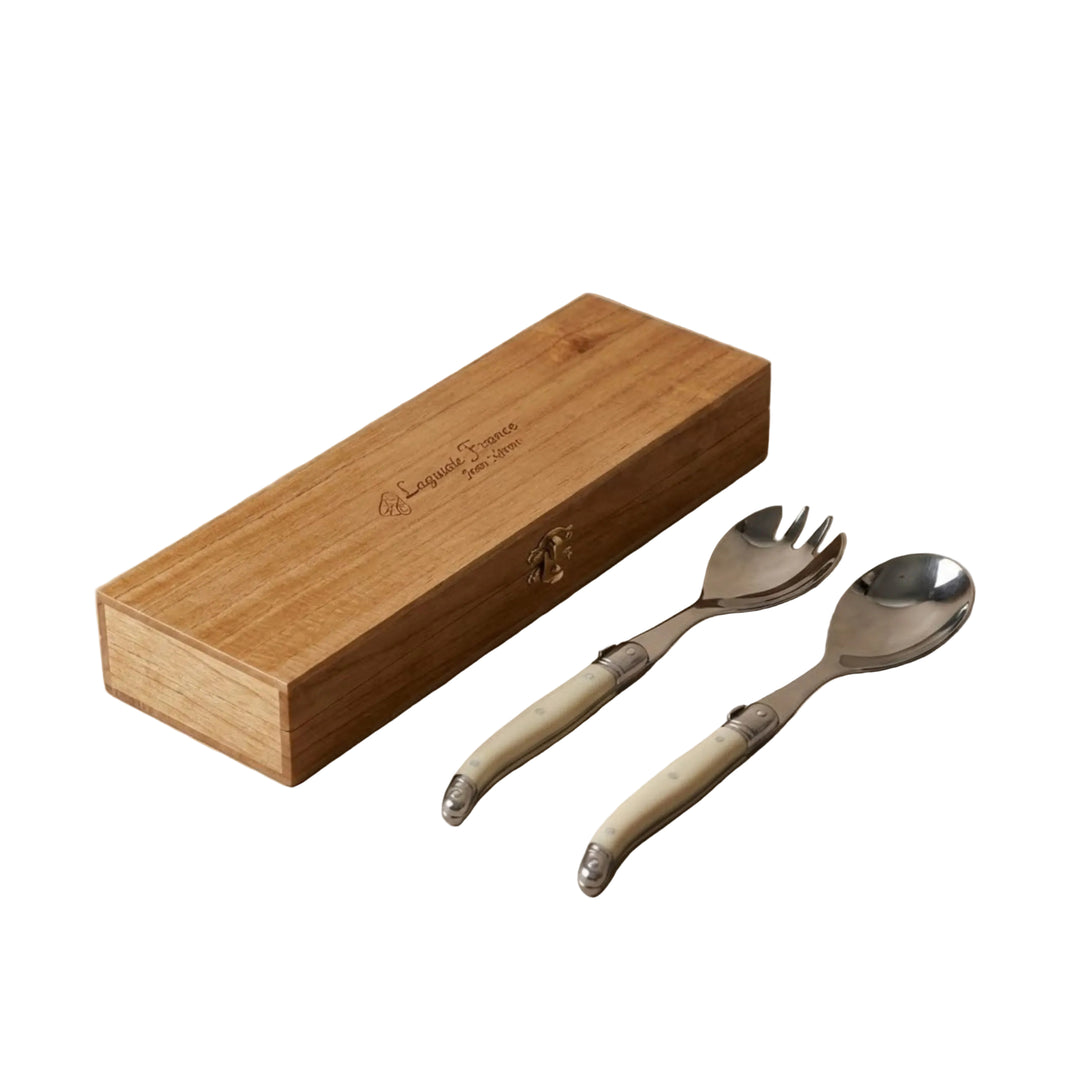 A serving set of a spoon and a spork with ivory handles nest to a wodden box with Laguiole France burned onto the lid