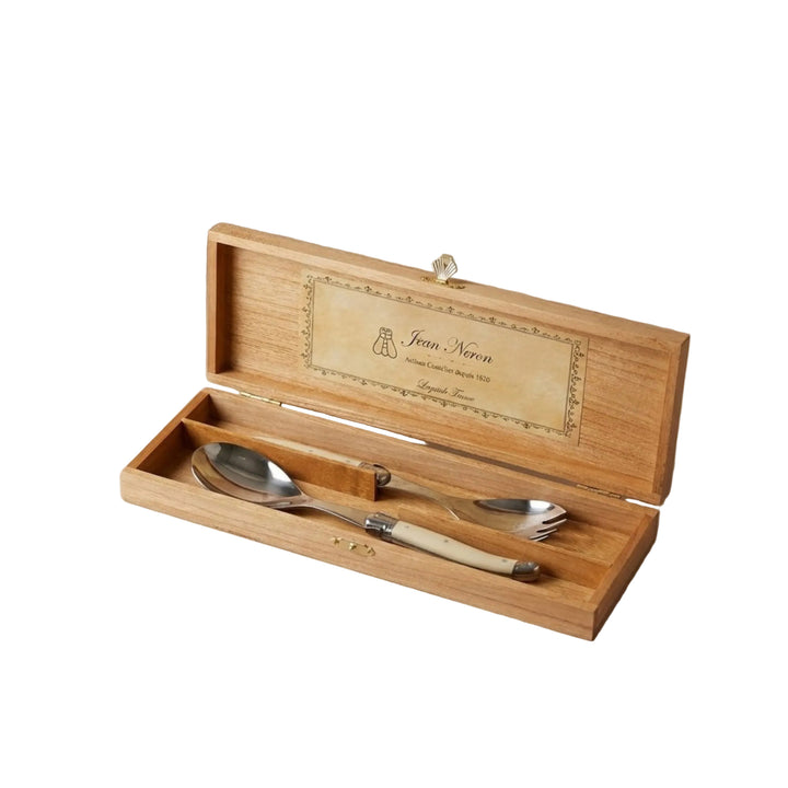 A wooden box with a label reading Jean Neron displaying a host serving set wirh ivory handles
