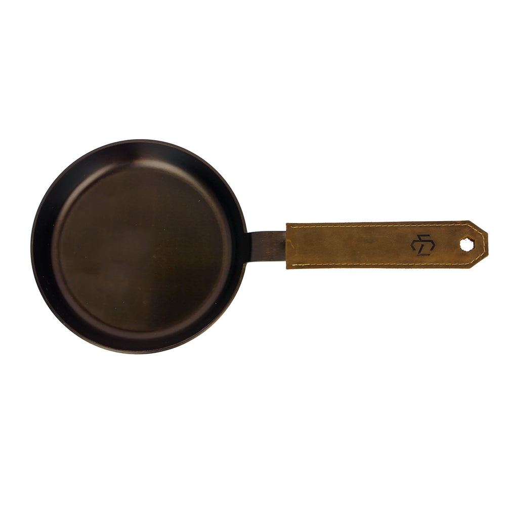 Small black carbon steel pan with brown leather handle sleeve