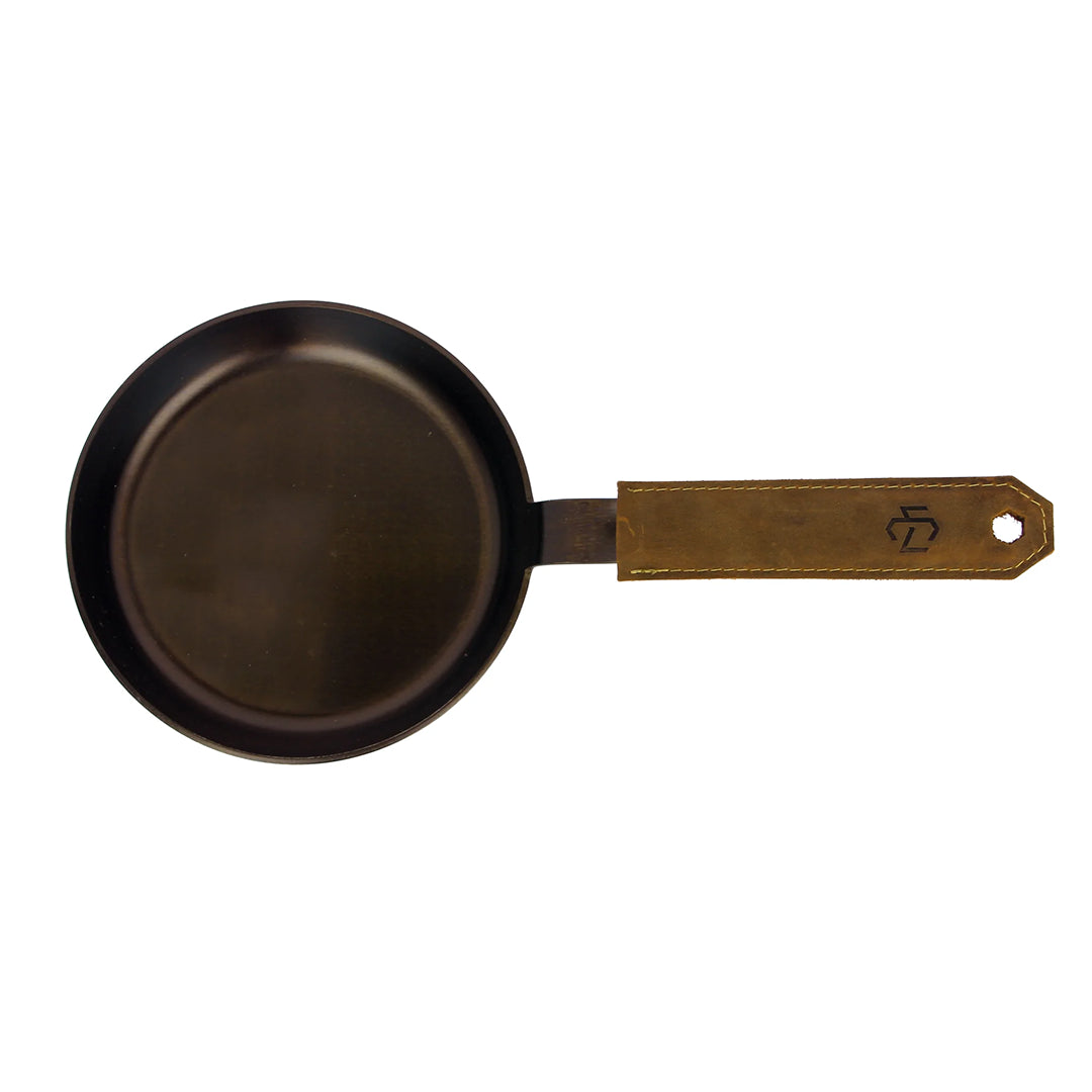 Small black carbon steel pan with brown leather handle sleeve