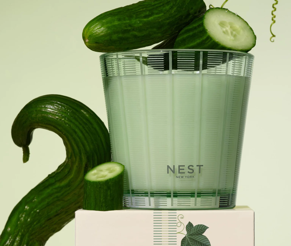 A nest cucumber and white sage three wick candle with decorative cucumbers