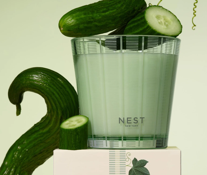 A nest cucumber and white sage three wick candle with decorative cucumbers