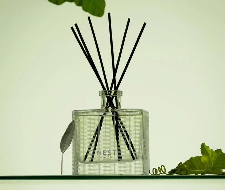 A nest cucumber and white sage reed diffuser with a sage leaf and cucumber leaves