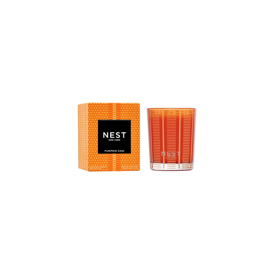 Orange pumpkin chai votive candle and packaging with 'NEST' branding on a white background