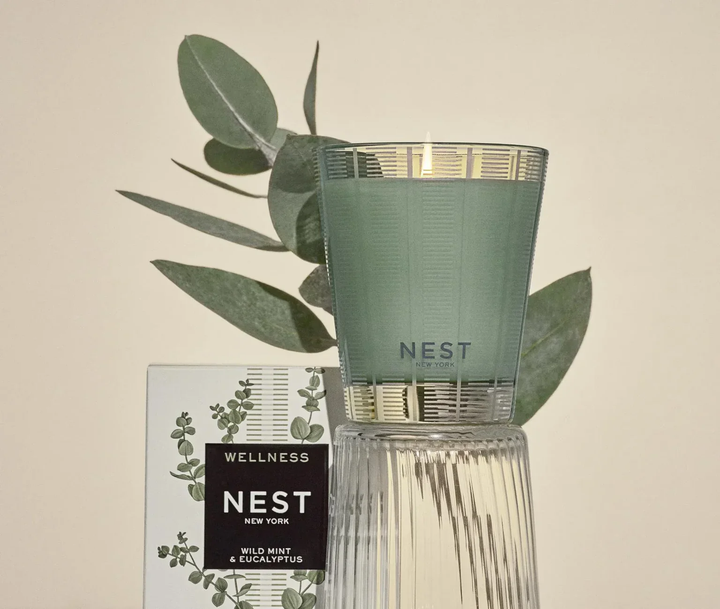Green Wild Mint and Eucalyptus candle with 'NEST' branding and eucalyptus leaves