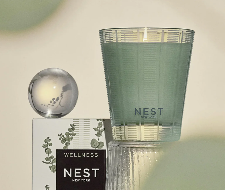 NEST New York Wild Mint and Sucalyptus candle next to packaging with a decorative glass orb sitting on top