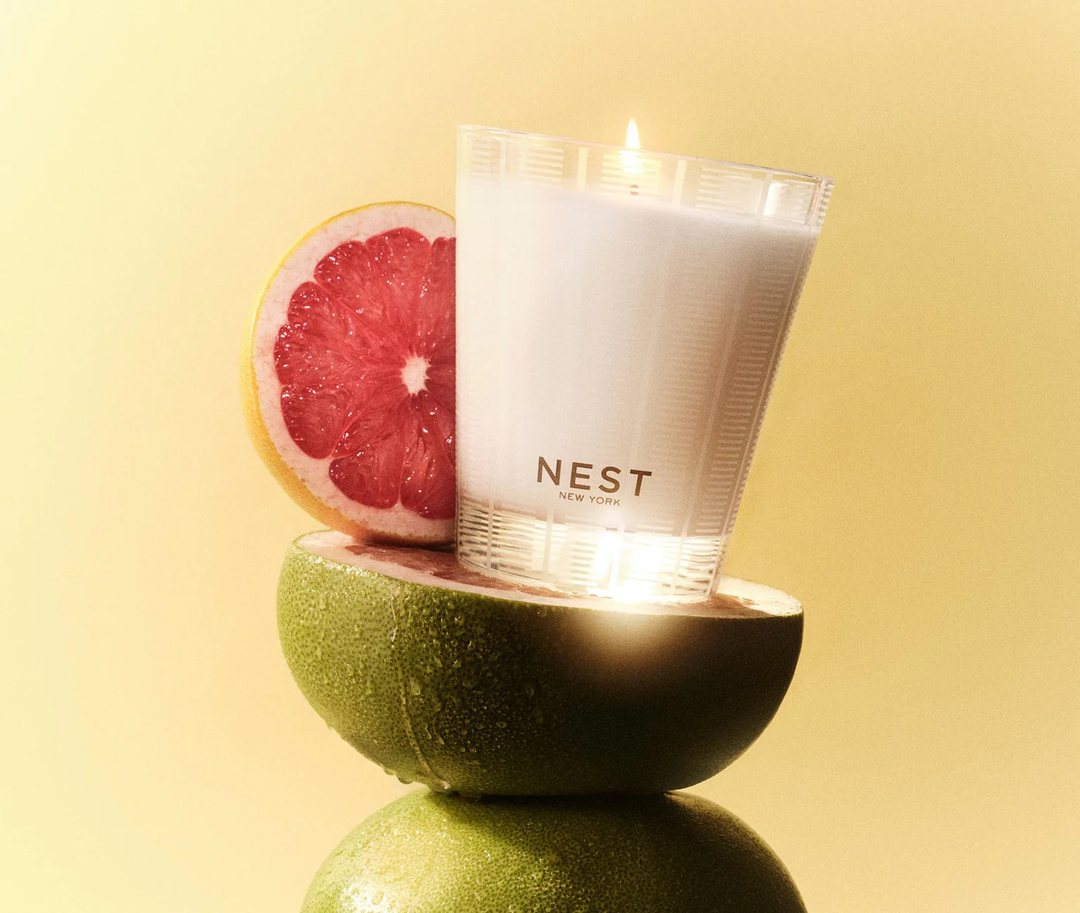 NEST candle inside a half-cut grapefruit with a grapefruit slice on a yellow background