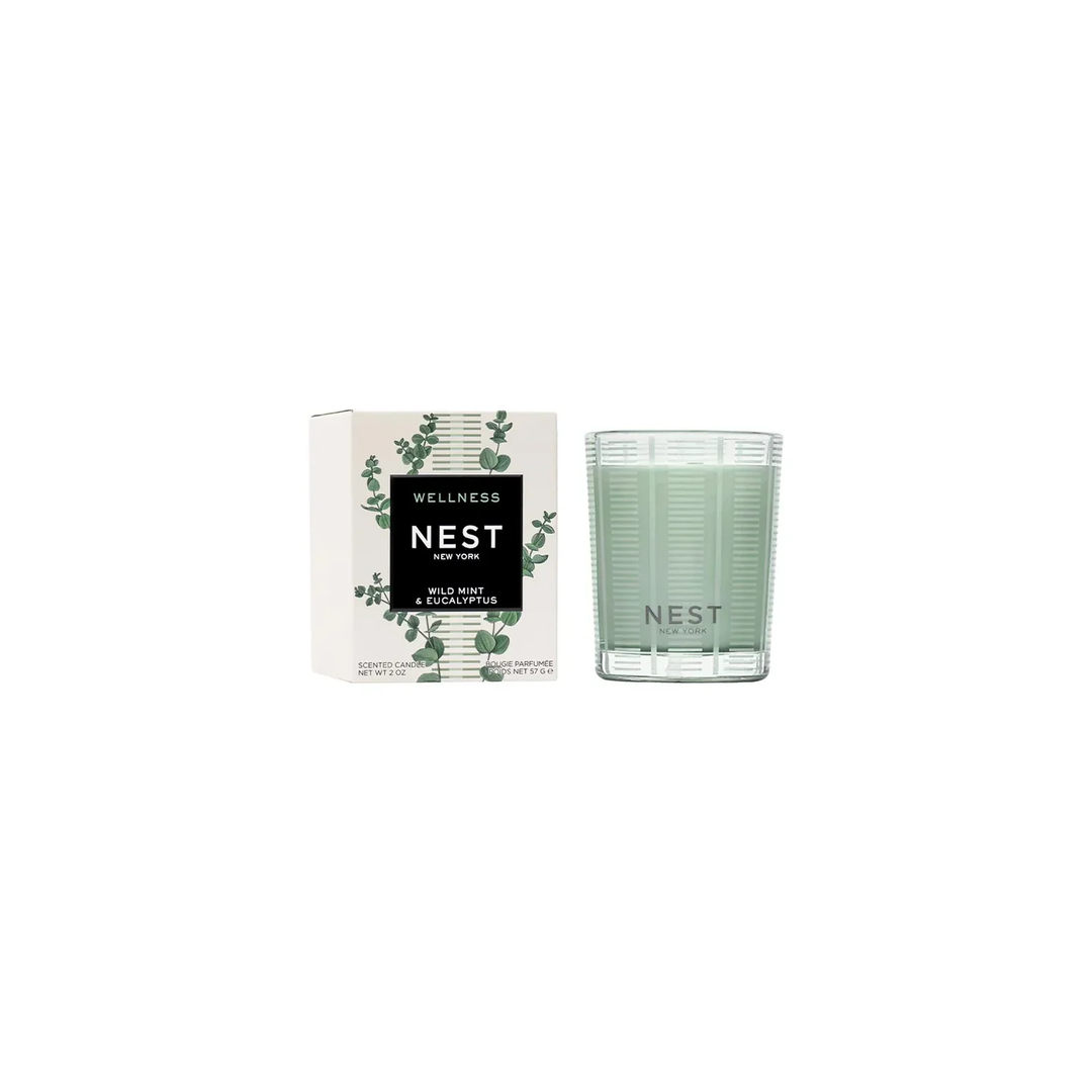 A Wild Mint and Eucalyptus votive candle by Nest sitting next to its packaging