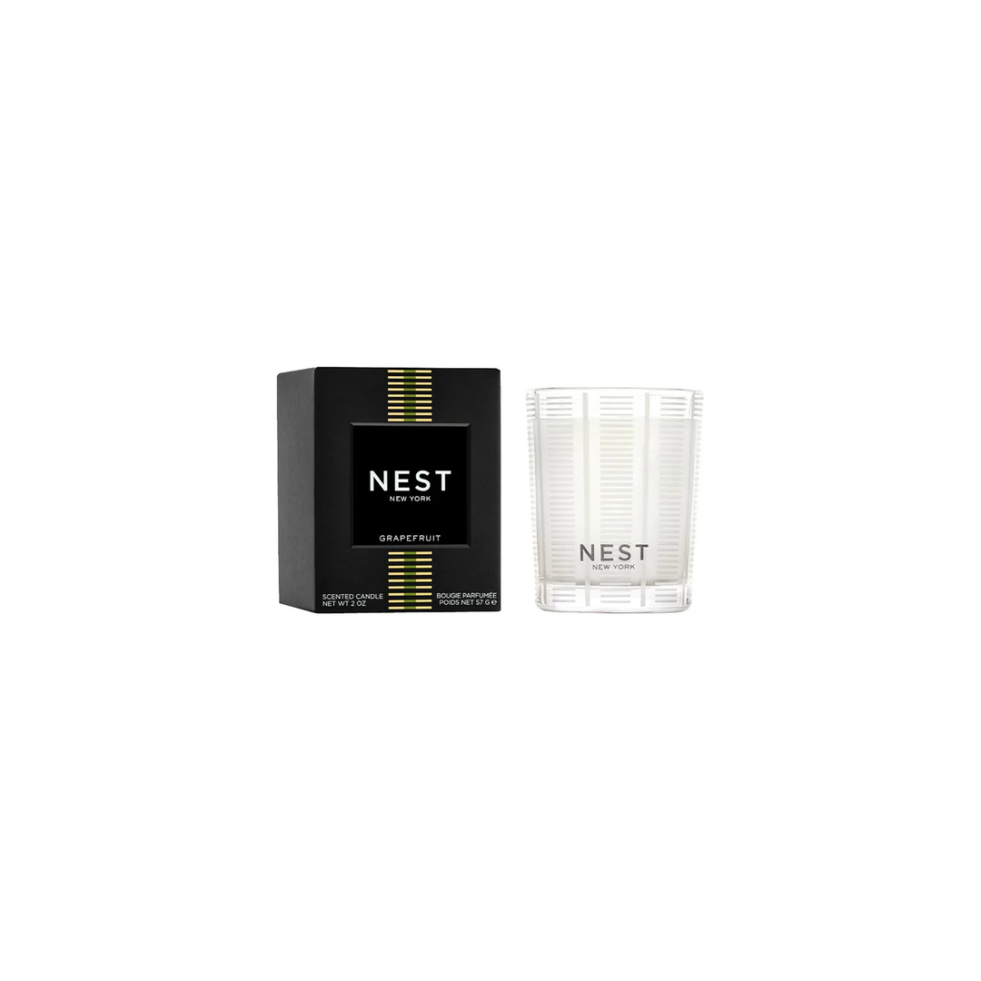 A nest grapefruit votive candle sitting next to its box