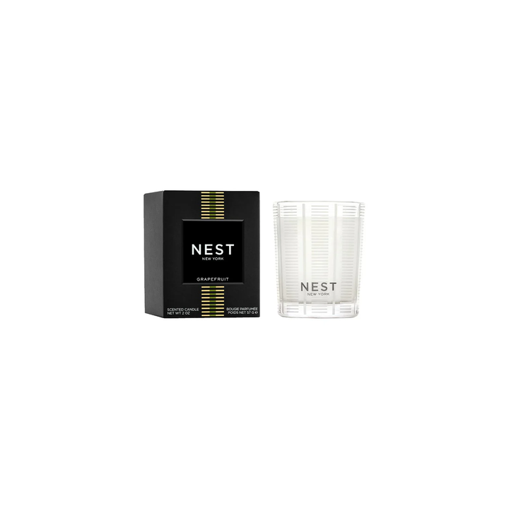 A nest grapefruit votive candle sitting next to its box