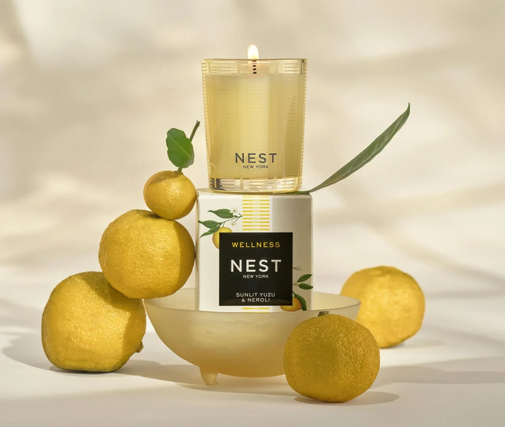 NEST New York Sunlit Yuzu and Neroli candle with lemons and a bowl on a light background