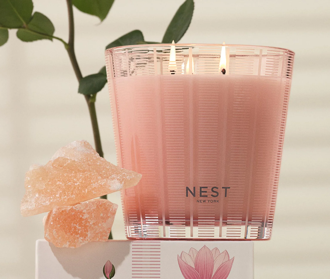 Pink nest Himalayan Salt and rosewater three wick candle next to pink salt rocks