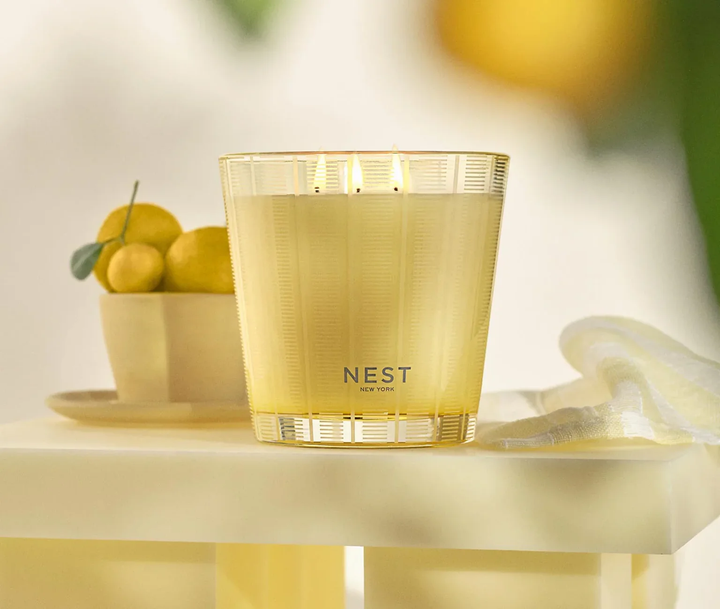 NEST New York sunlit yuzu and neroli  candle on a table with a bowl of yuzu fruits