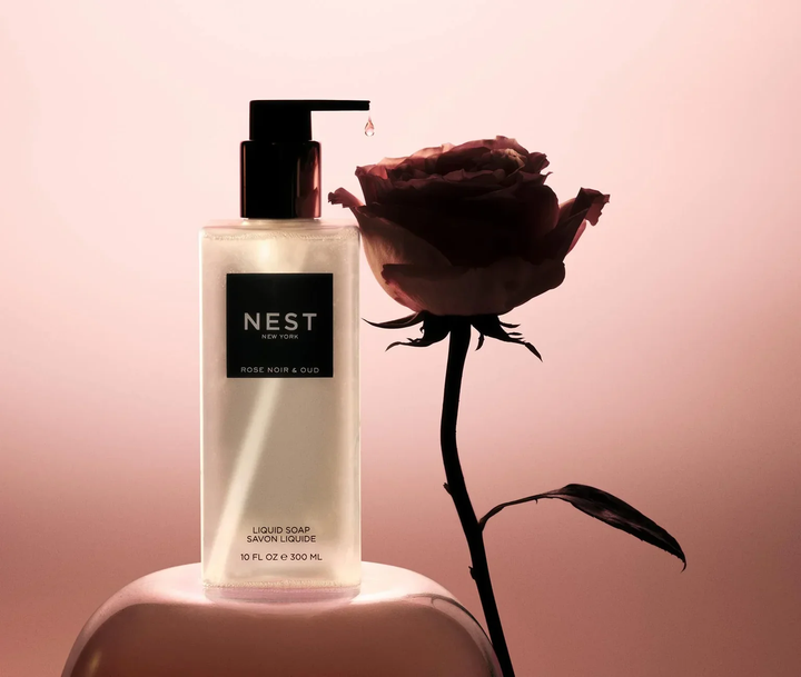 NEST Rose Noir and Oud liquid soap bottle with a rose on a pink background