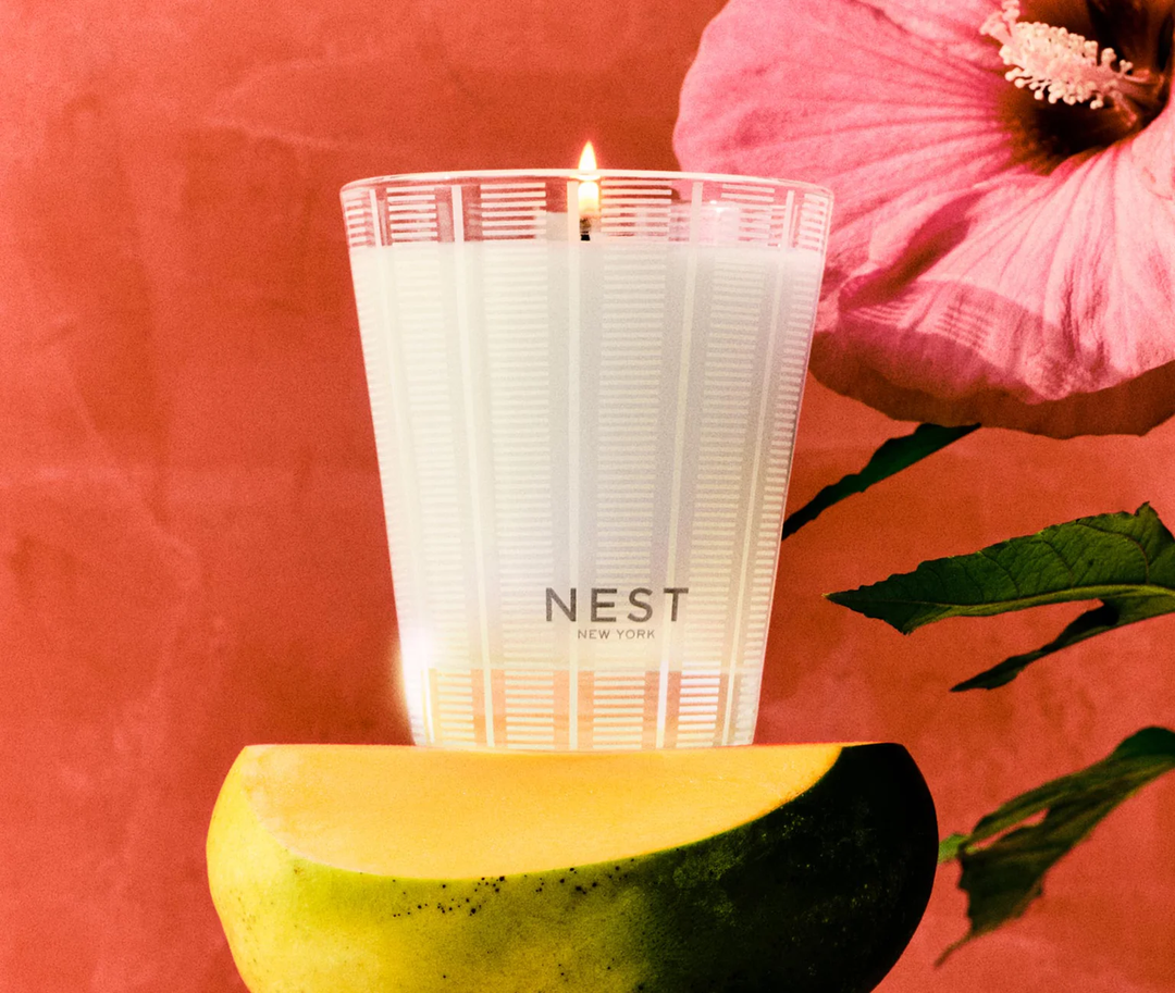 NEST New York Something Tropical candle on a mango with a pink Rose of Sharon flower in the background
