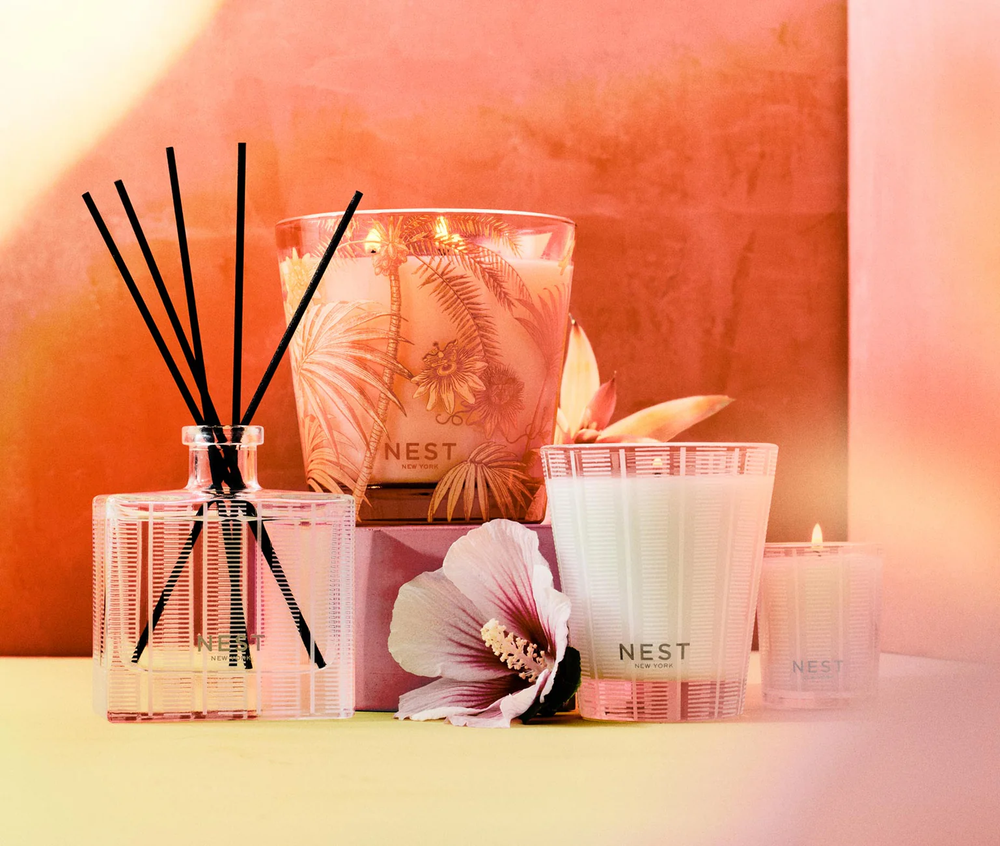 Nest Something Tropical three wick, classic, and votive candles and reed diffuser with a Rose of Sharon  on a soft pink background 