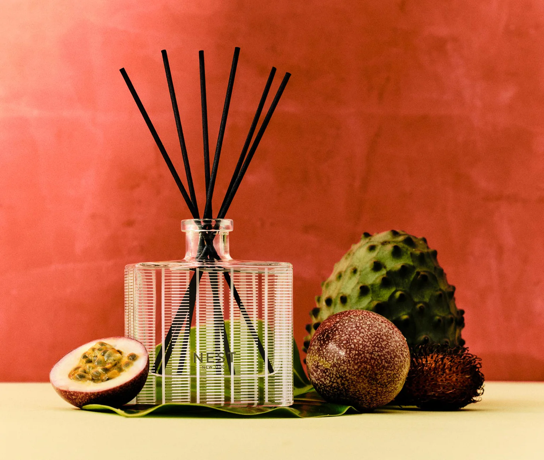 A nest Something Tropical Reed diffusser with decorative passionfruits, rambutan, and a soursop