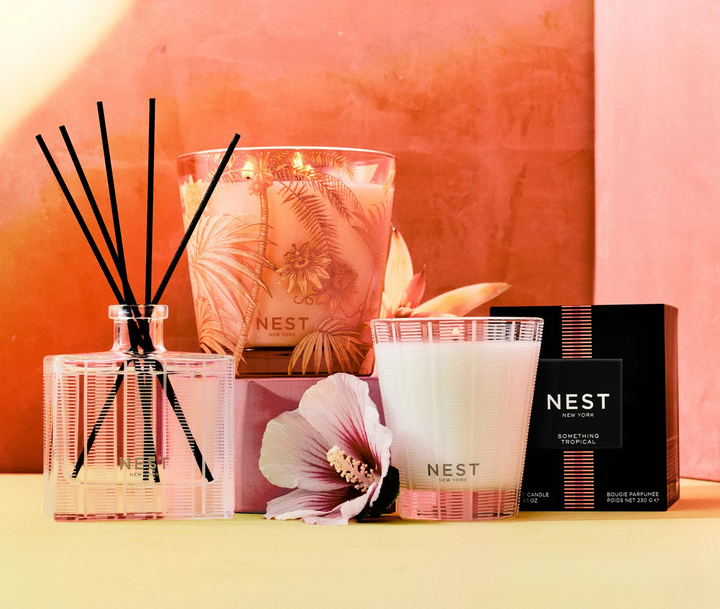 NEST New York classic and decorative Something Tropical candles and reed diffuser set with a roase of sharon flower against a pink background