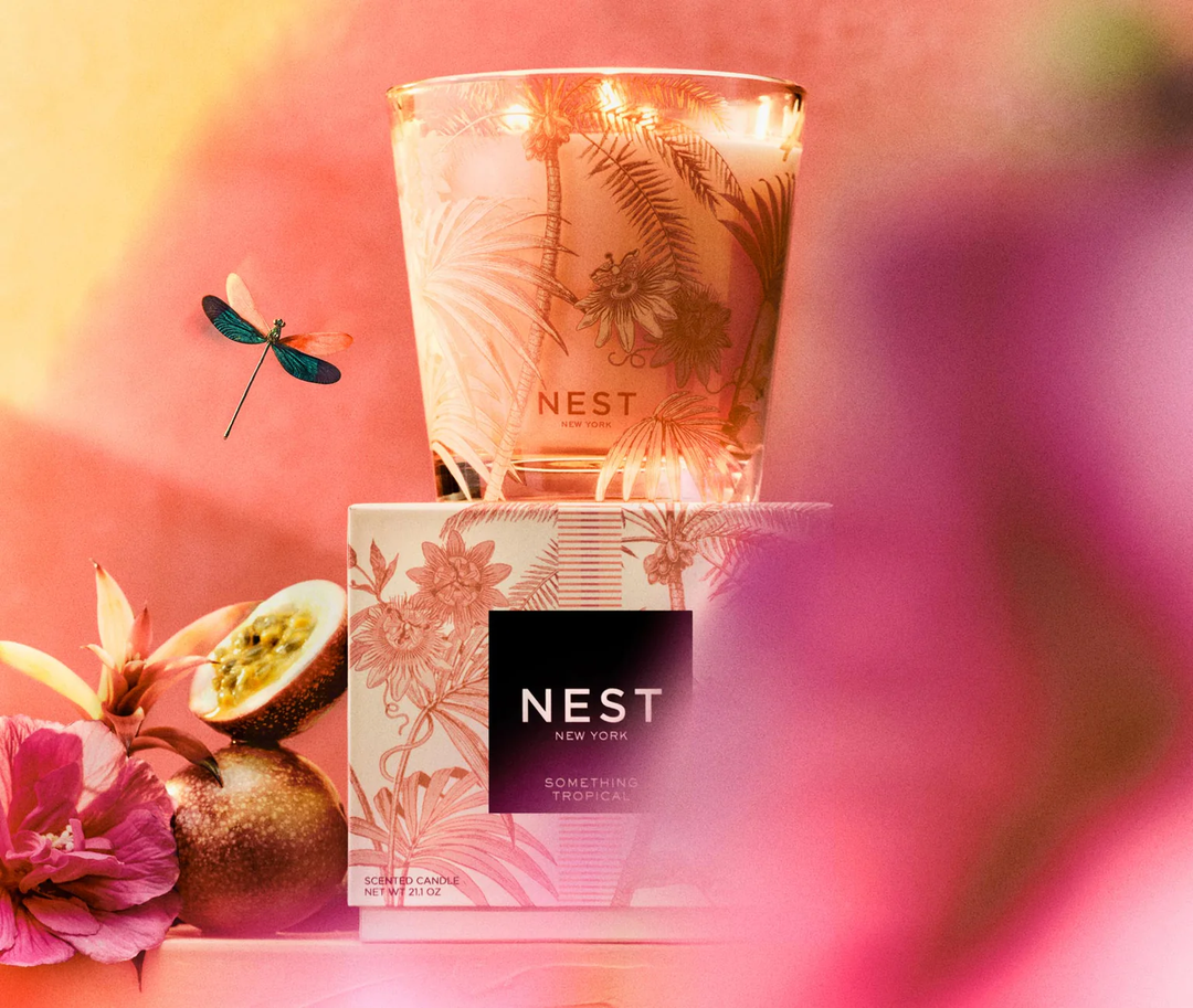 Nest three wick Something Tropical Candle with passionfruit, bromelaid flower, and a rose of sharon and a dragonfly decorating the shot