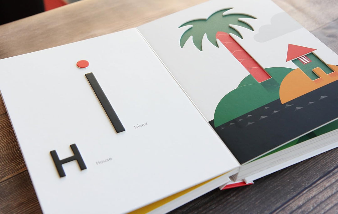 Open book with colorful illustrations of a beach scene and letters 'H' and 'I'.