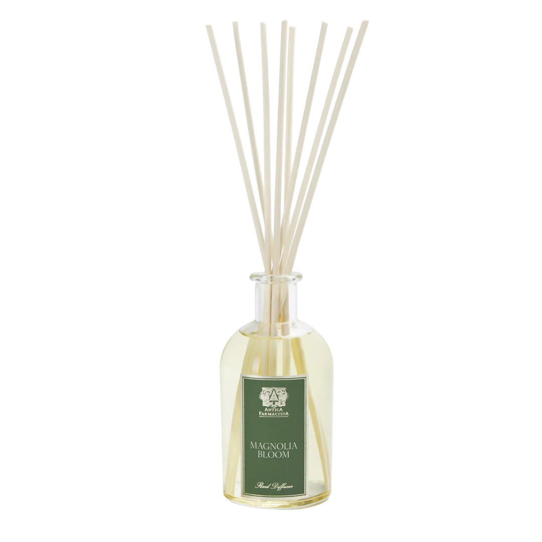 A reed diffuser with a green label reading "Magnolia Bloom"