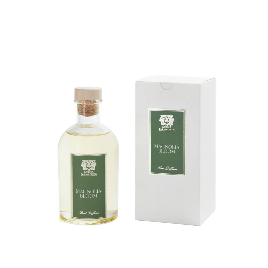 A bottle of reed diffuser oil witting next to a box labeled "Magnolia BLoom"