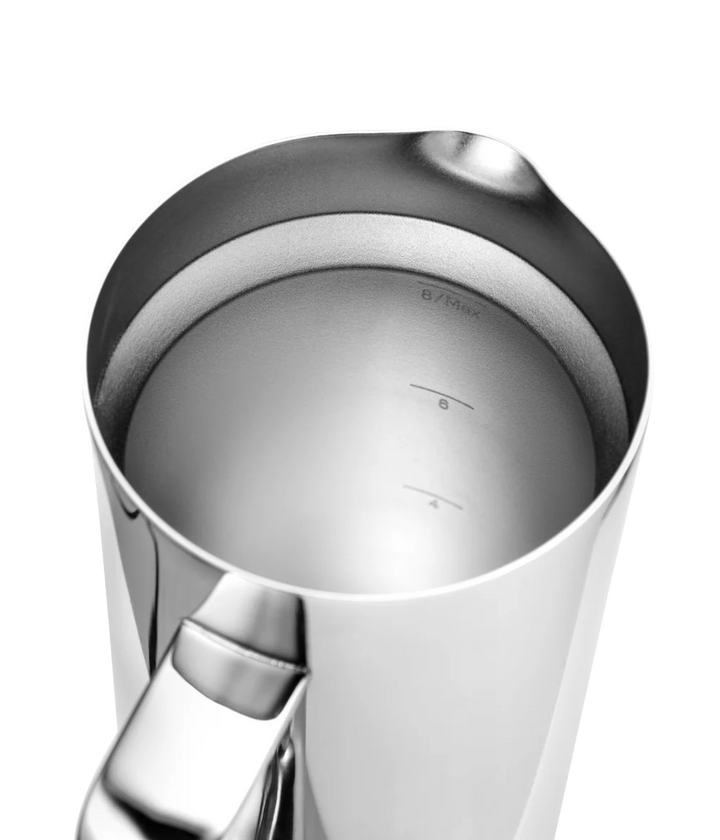 Close-up of a stainless steel milk pitcher with a pouring spout and handle, showing measurement markings inside on a white background.