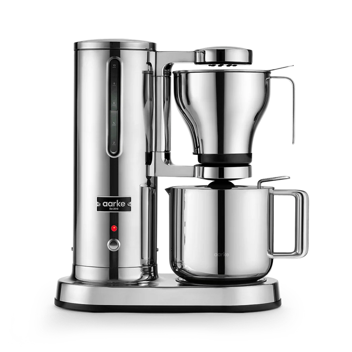 A sleek, professional drip coffee maker in polished stainless steel, featuring a tall water reservoir, a conical filter basket, and a large carafe on a white background.