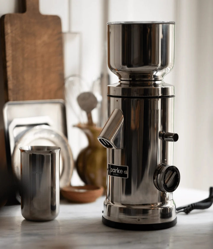Stainless steel coffee grinder on a kitchen counter with blurred background