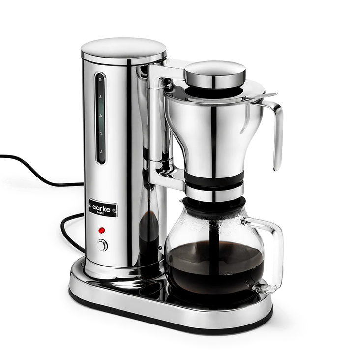 A sleek chrome and black coffee maker with a glass carafe filled with dark coffee, shown on a clean white background. The brand name 'marke' is visible on the front of the unit.