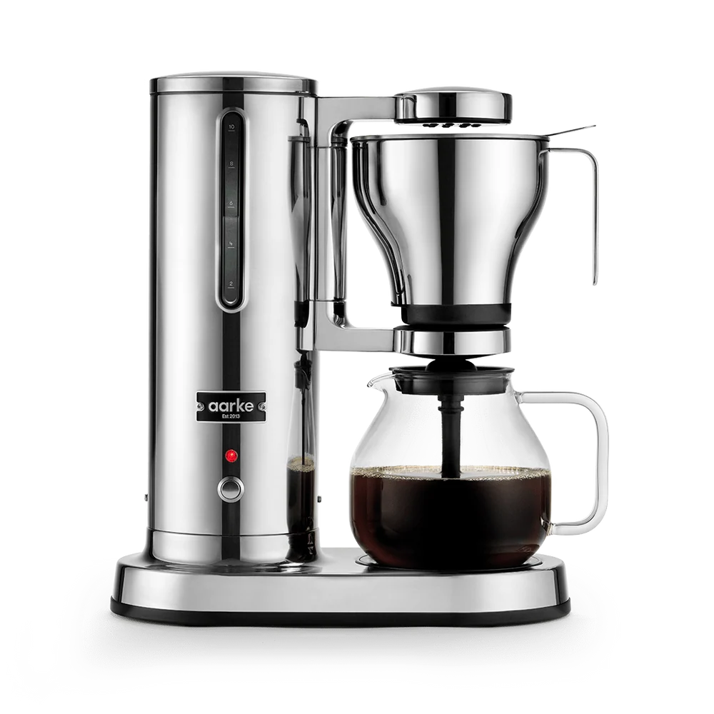 A sleek aarke coffee maker with a polished stainless steel body, a clear glass carafe containing dark coffee, and a matching glass dripper, shown on a clean white background.