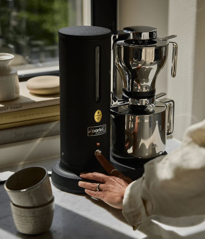 Coffee grinder with a person operating it on a kitchen counter.