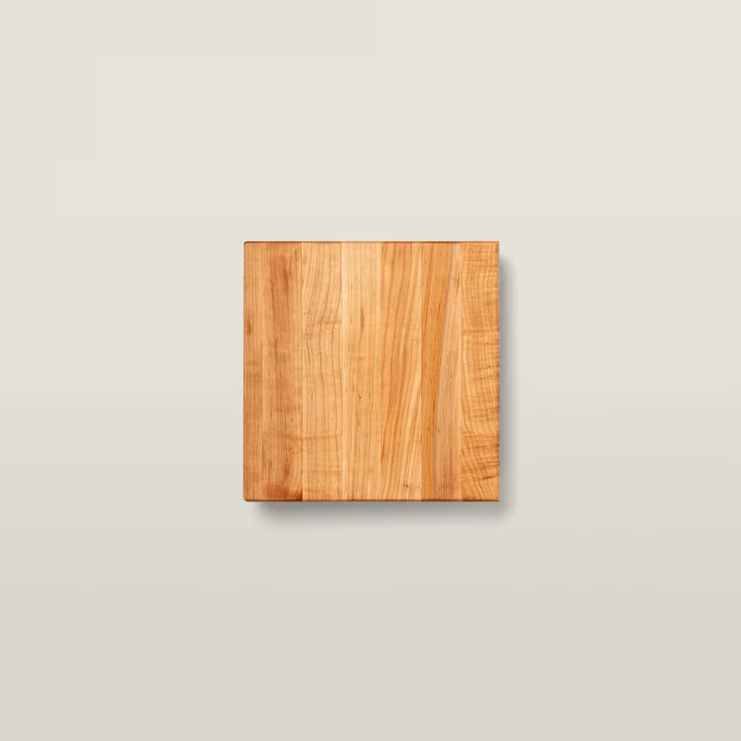 A square wooden board with a warm honey-brown wood grain finish, centered on a light beige background.