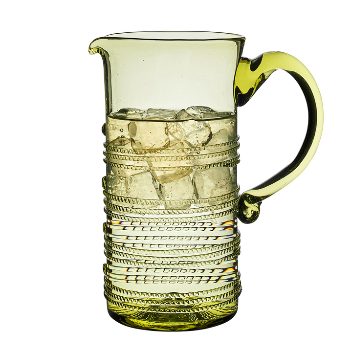 Green glass pitcher with decorative patterns on a white background