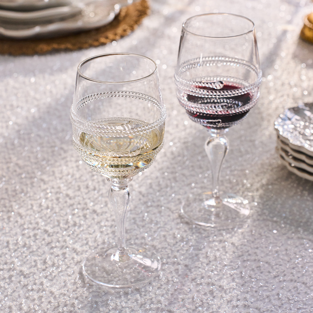 Two wine glasses on a glittery surface, one with white wine and the other with red wine.