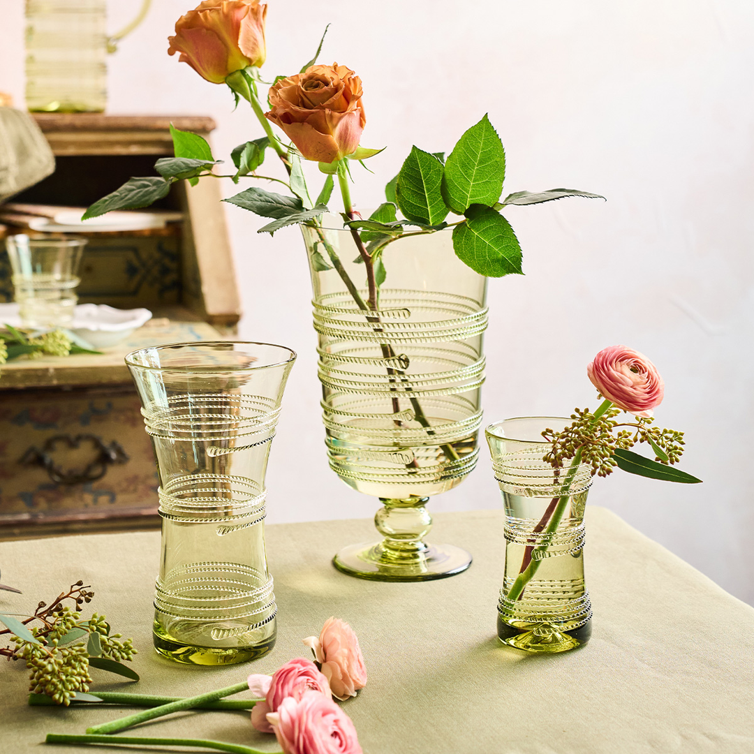 Set of green glass vases with floral arrangements on a table.