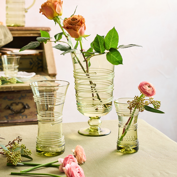 Set of green glass vases with floral arrangements on a table.