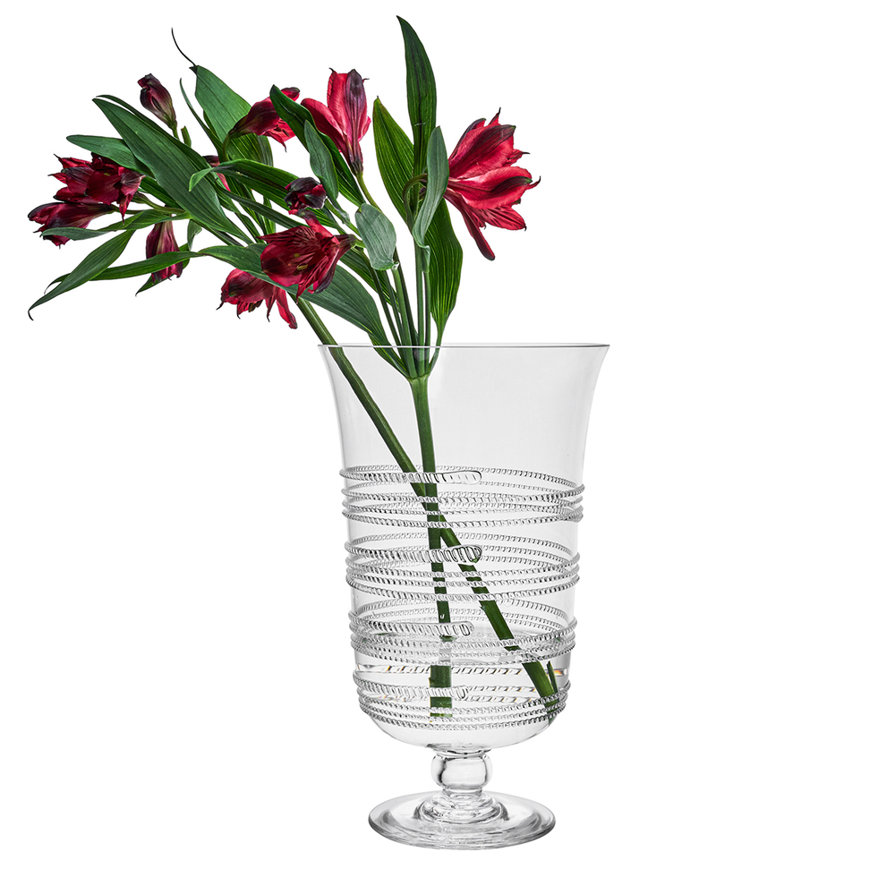 Clear glass vase with ribbed design holding red flowers on a white background