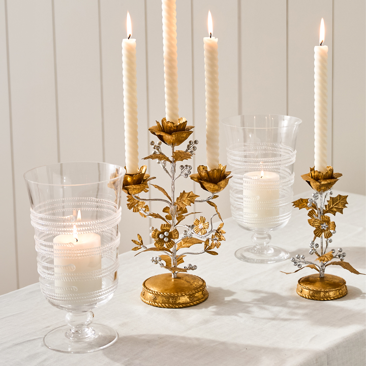 Decorative candle holders with candles on a white surface and light wooden background