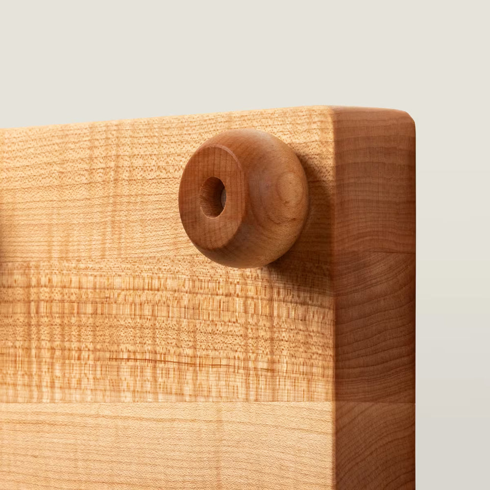 Wooden cutting board with a round handle on a light background