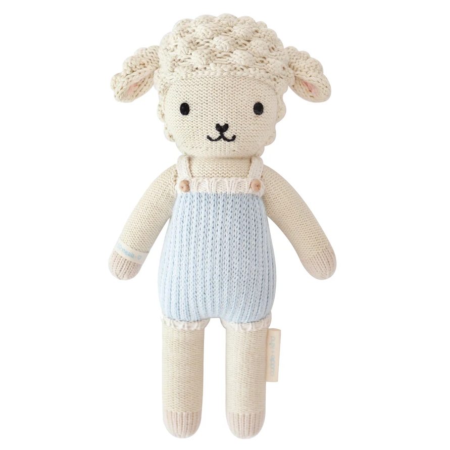A knitted plush toy sheep with cream-colored wool and body, wearing light blue knit overalls