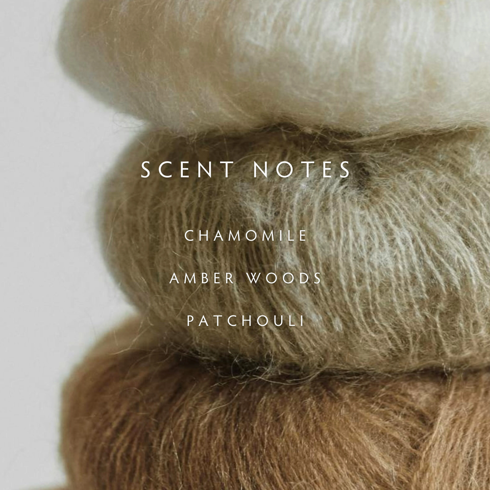 A stack of earth tone wool skeins with the words "scent notes, chamomile, amber woods, patchouli" overlaid